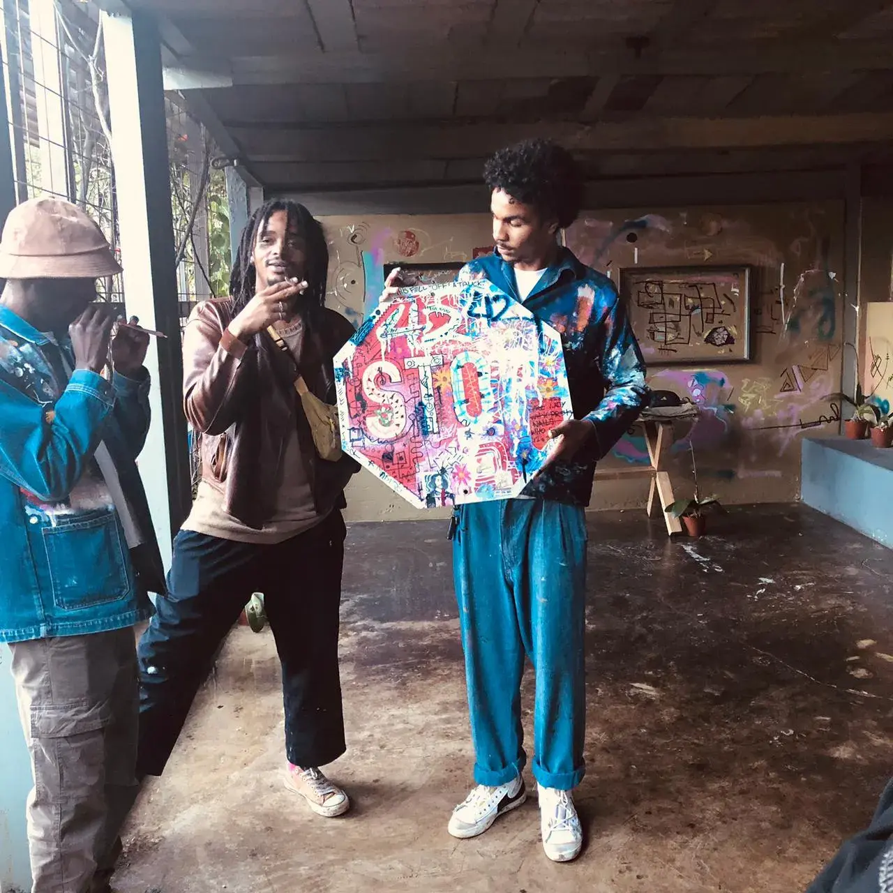 Three men in graffiti studio with stop sign