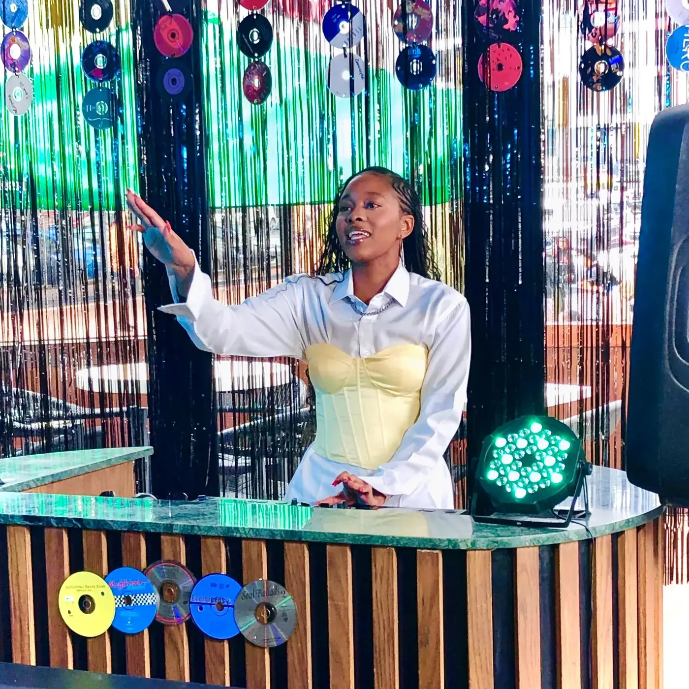 DJ behind green marble booth, hand raised